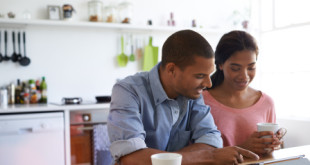 Shot of a young couple sitting at their dining table using a digital tablet