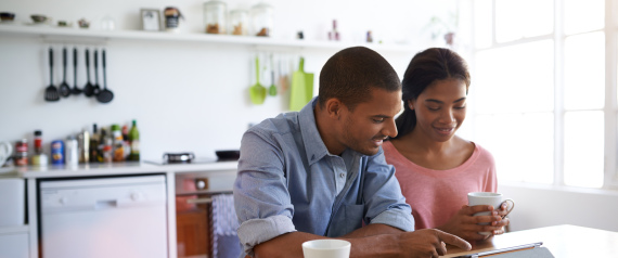 Shot of a young couple sitting at their dining table using a digital tablet