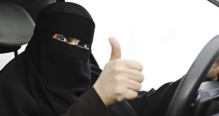 Excited Arabic Muslim woman with veil and scarf  driving car